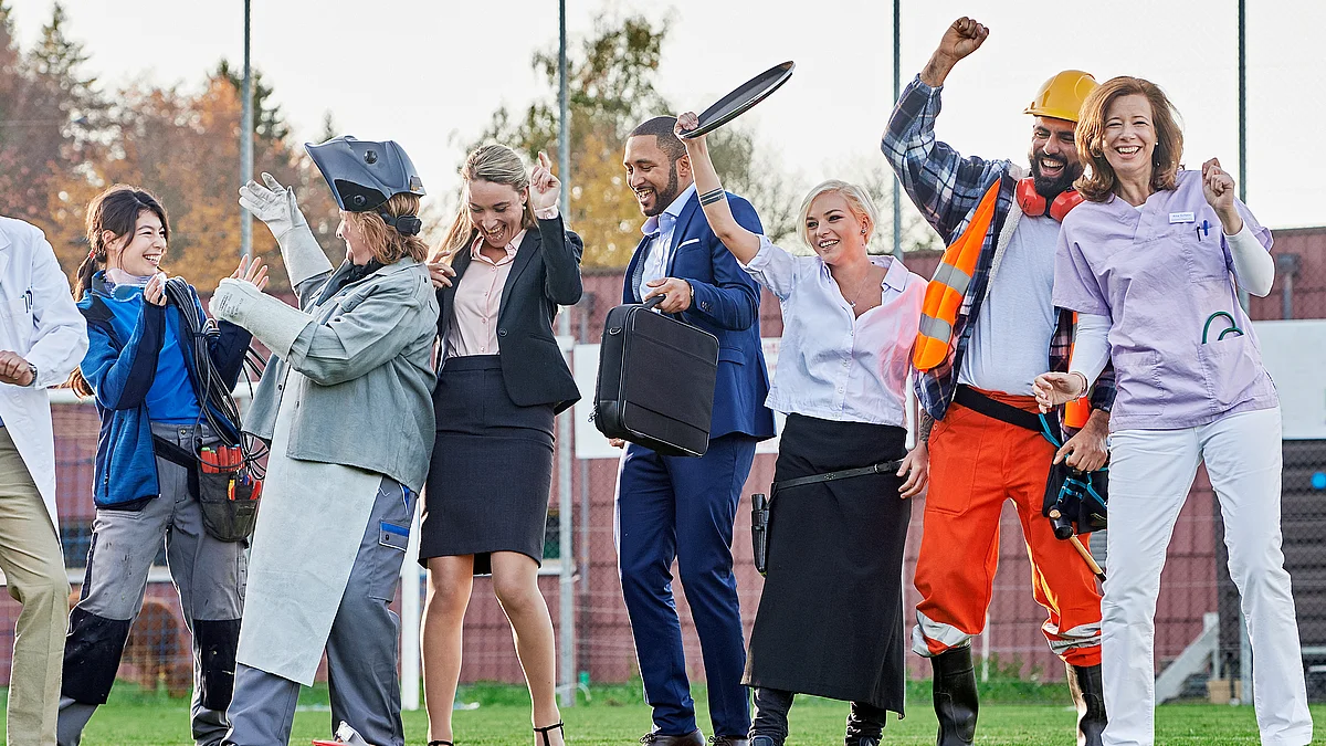 A cheerful group of people in various professional outfits celebrate together, symbolising unity and diversity in working life.