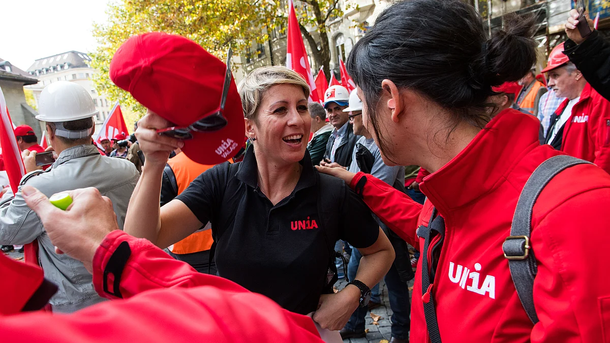 A group of people, many wearing Unia clothing, are cheerfully participating in a union demonstration.